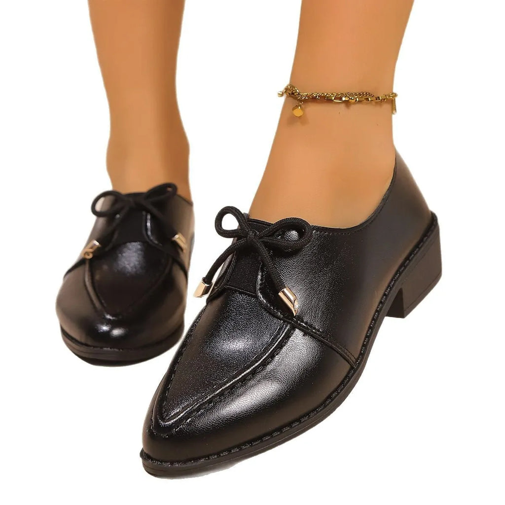 Women's brown leather-look shoes with a decorative bow detail on a flat rubber sole