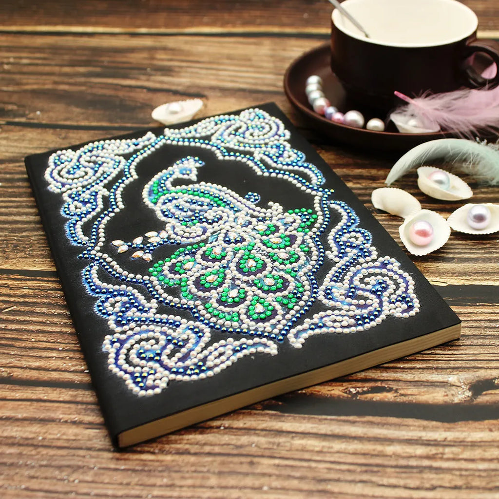 Black A5 diamond painting notebook with a peacock design cover, shown closed.