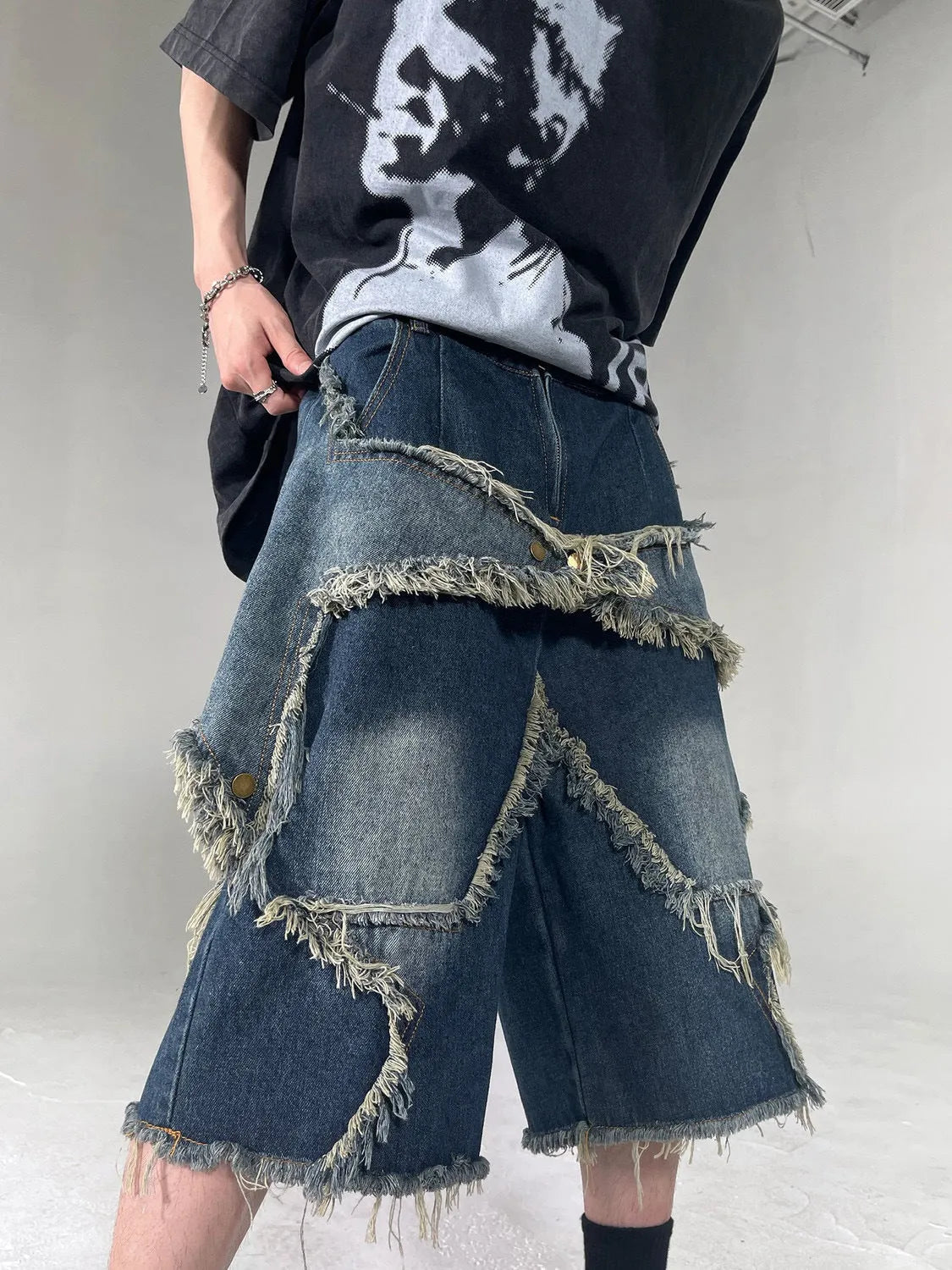 Men's blue distressed denim shorts with a large five-pointed star and frayed hem in a loose cargo fit.