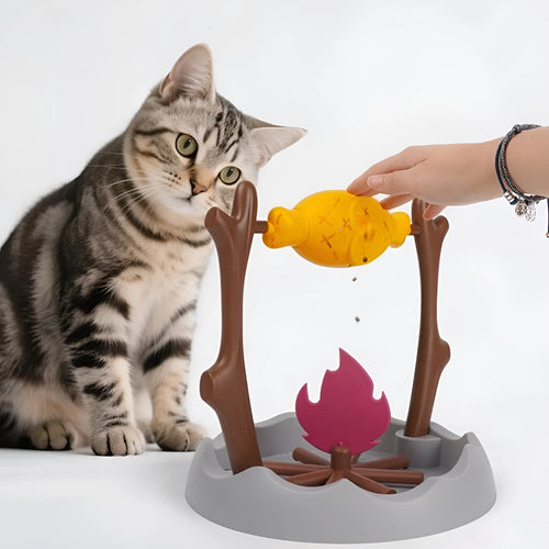 White and grey tumbling cat feeder toy with treat compartment on a wooden floor.