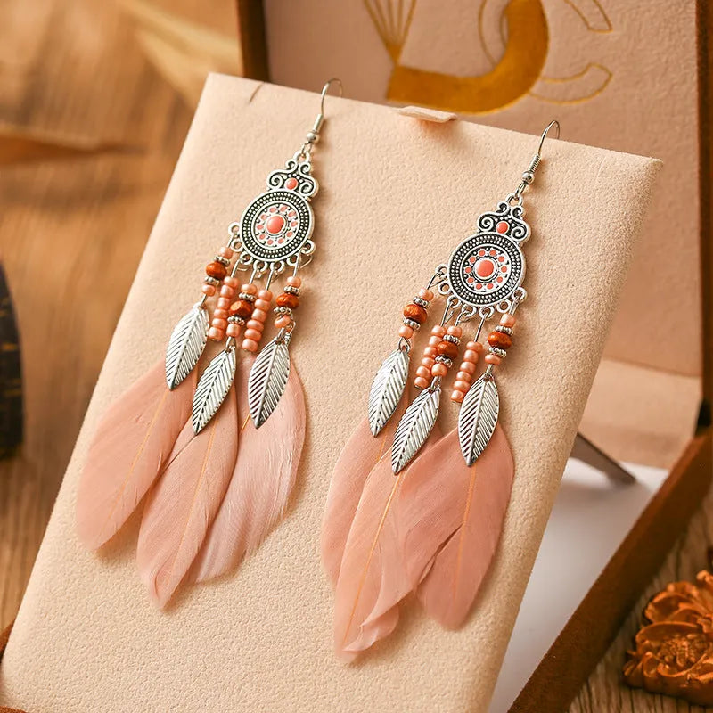 A pair of round drop leaf-shaped feather earrings in a chosen colour, showing Bohemian pattern details.
