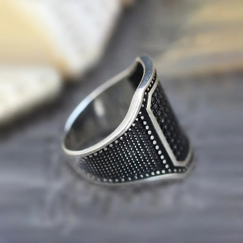 Black alloy ring with copper inlay and a central zircon stone, shown in size 10.