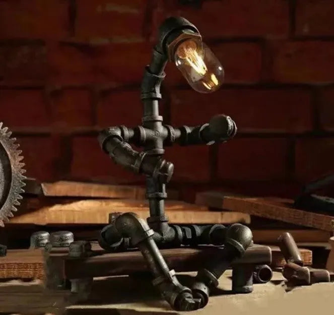 Green bronze vintage industrial robot desk lamp with iron pipe design on a wooden table.