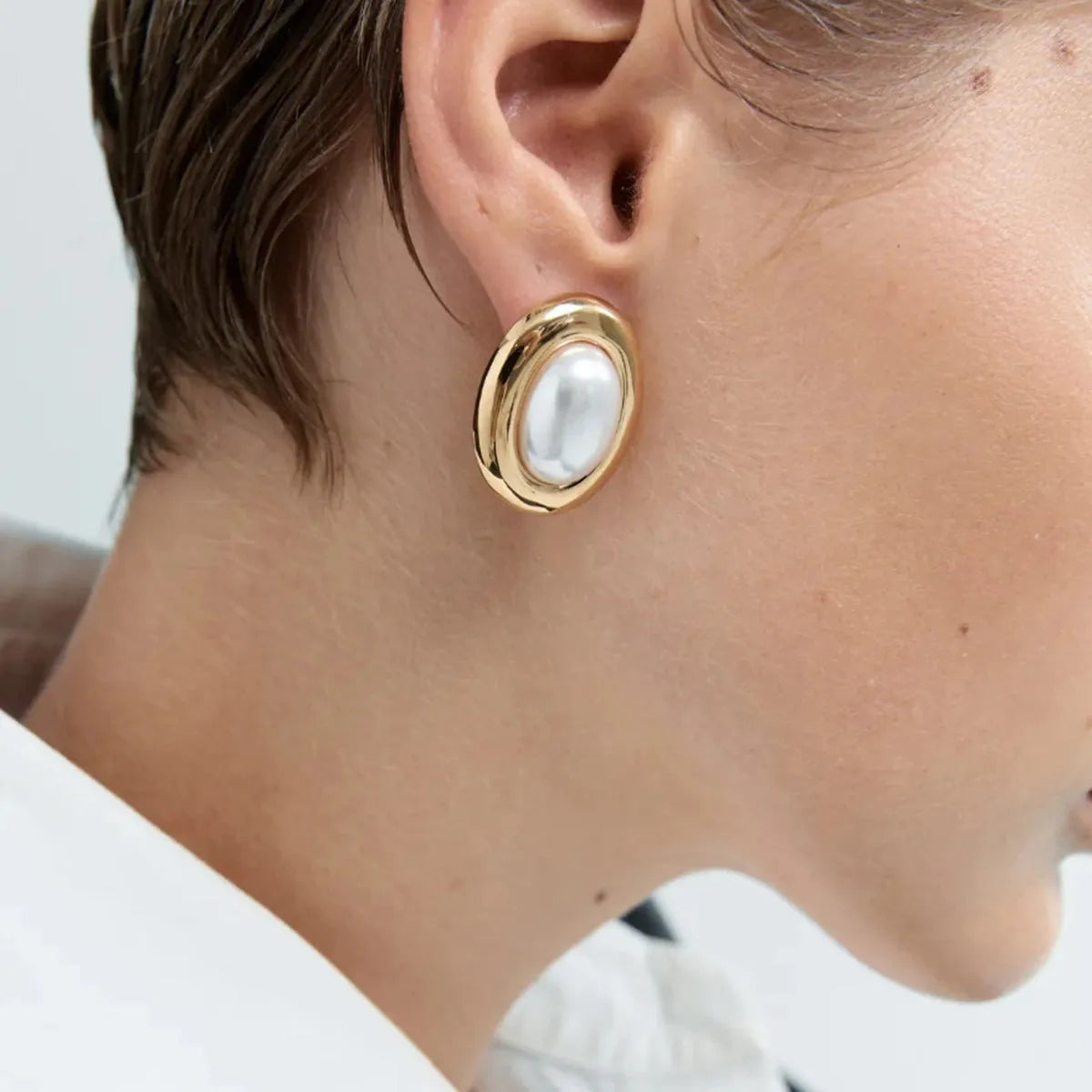 Close-up of a pair of stainless steel vintage-style stud earrings with a pearl detail in JDE0305051 colour.
