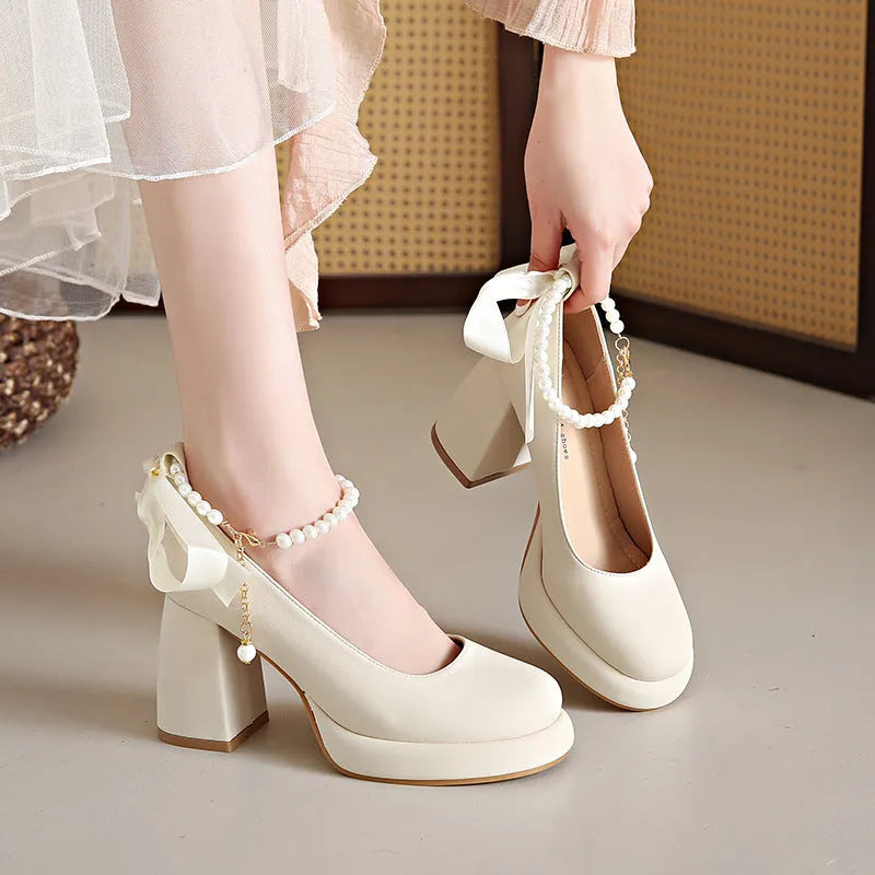 Women's beige Mary Jane shoes with chunky heel, round toe, and ankle strap with pearl buckle.