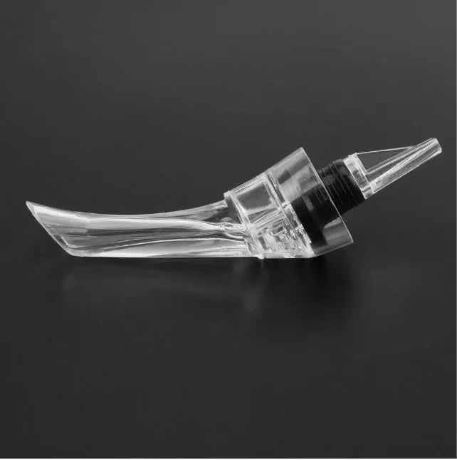 Compact clear acrylic wine aerator with a stainless steel filter insert on a wooden table.