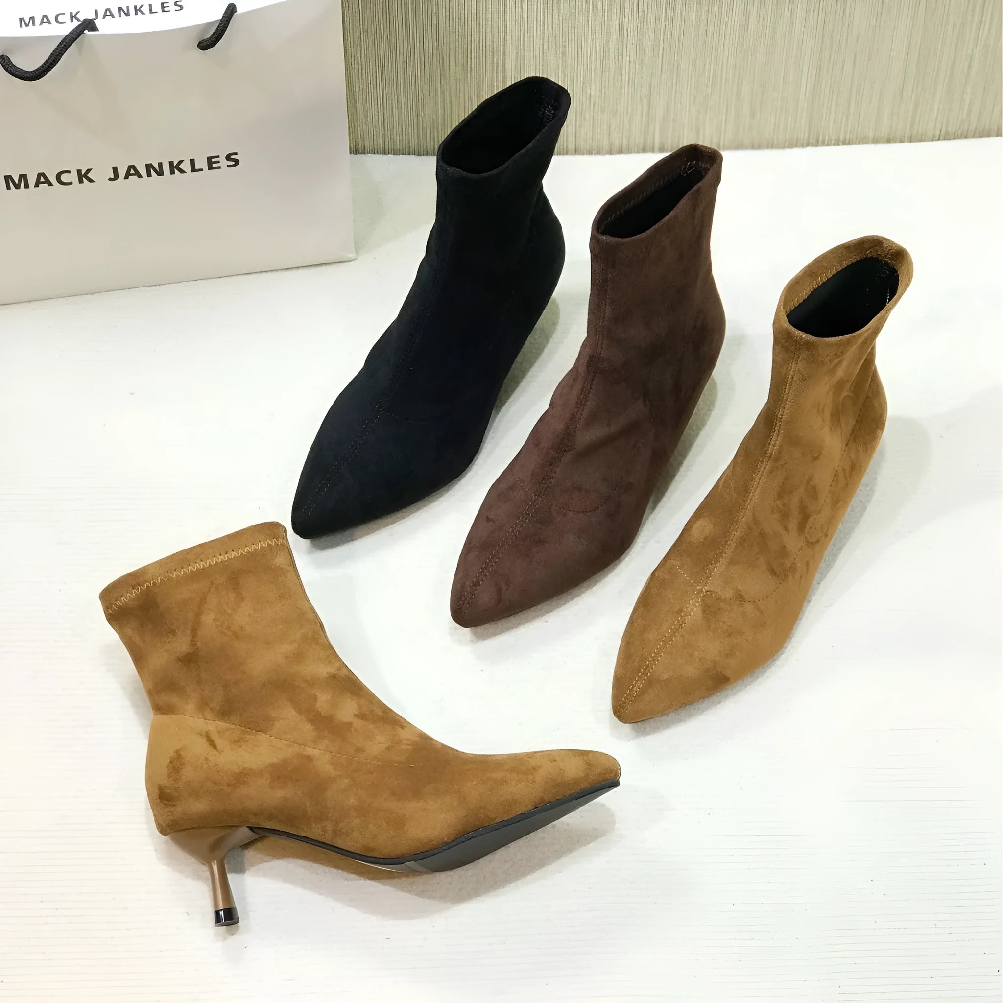 Black pointed toe ankle boots with a high stiletto heel on a woman's foot.