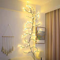 Flexible willow vine LED garland with birch bark texture and warm white lights shaped on a wall.