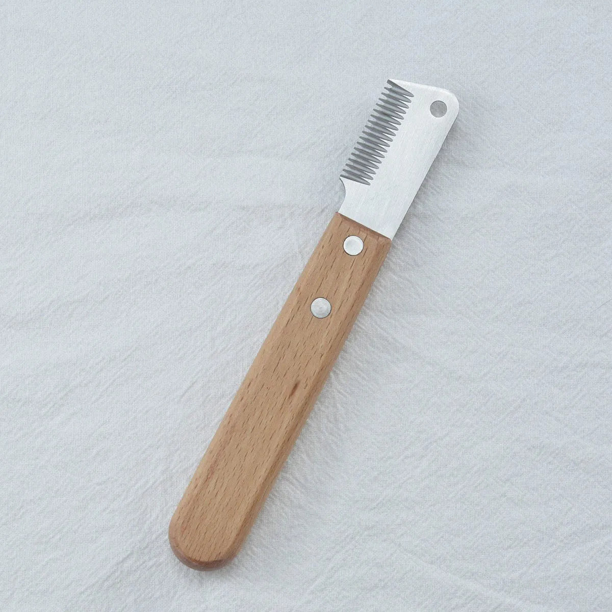 Pet stripping comb with wooden handle and metal teeth for removing hair from dogs and cats.