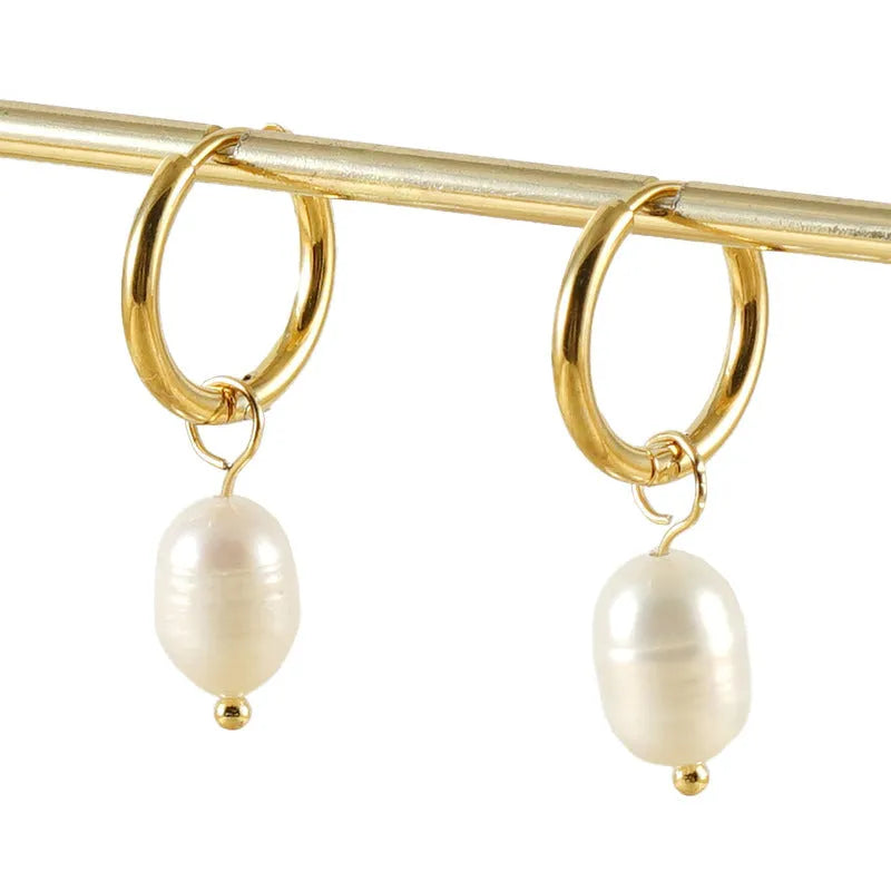 Geometric gold-coloured earrings with cultured pearl details on a white background.