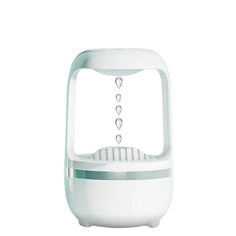 White anti-gravity water droplet humidifier on a wooden desk with visible mist and upward-flowing water beads.