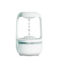 White anti-gravity water droplet humidifier on a wooden desk with visible mist and upward-flowing water beads.