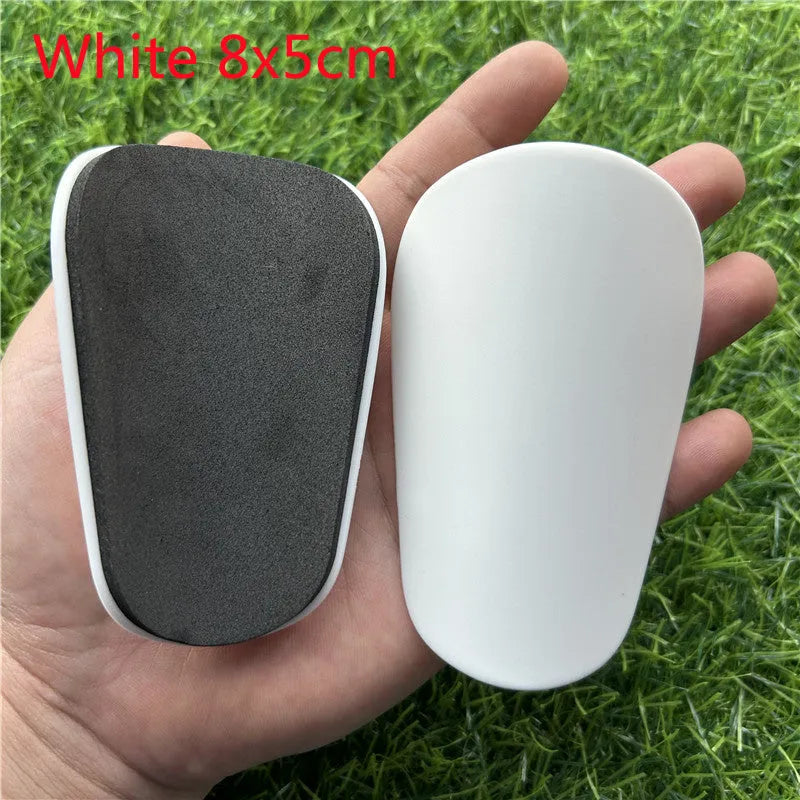 Extra small black and white plastic football shin guards measuring 8x5cm and 10x6cm