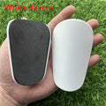 Extra small black and white plastic football shin guards measuring 8x5cm and 10x6cm