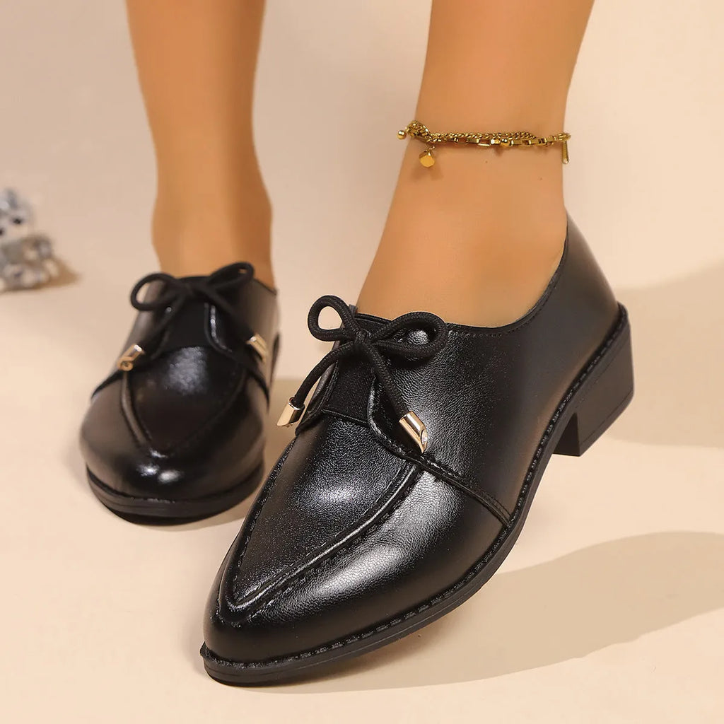Women's brown leather-look shoes with a decorative bow detail on a flat rubber sole