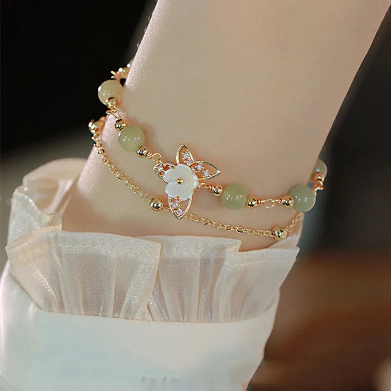 Yellow gold electroplated copper bracelet with a geometric bells of Ireland butterfly and Hetian jade design for women.