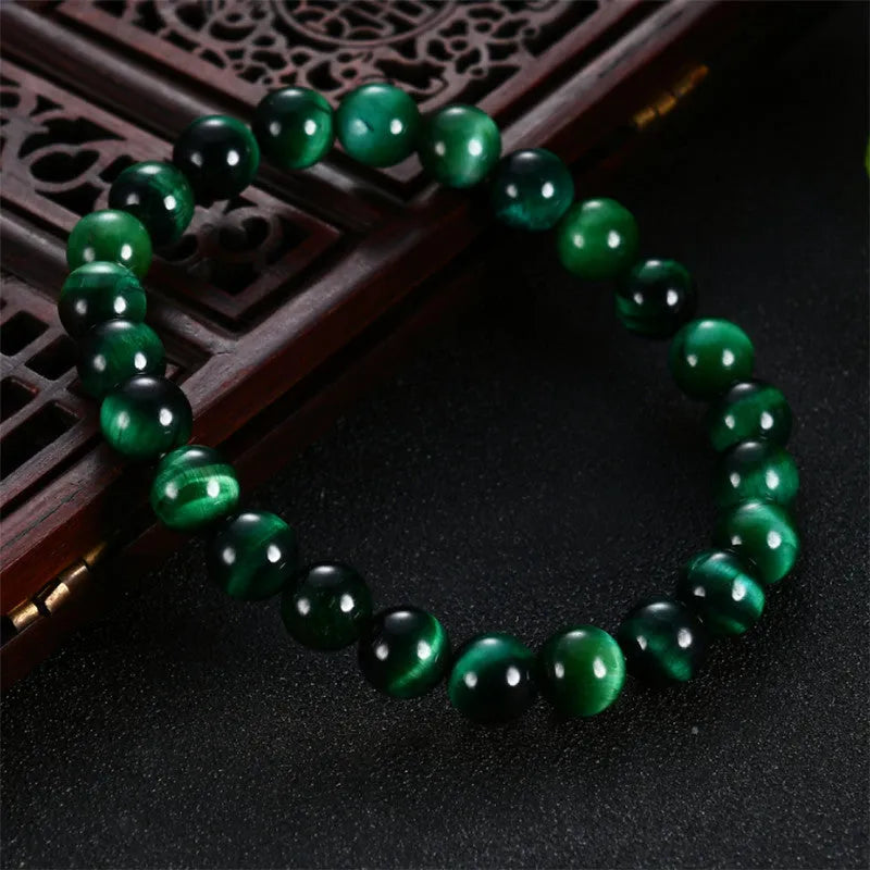 Green tiger eye stone bracelet with geometric beads on a wrist.