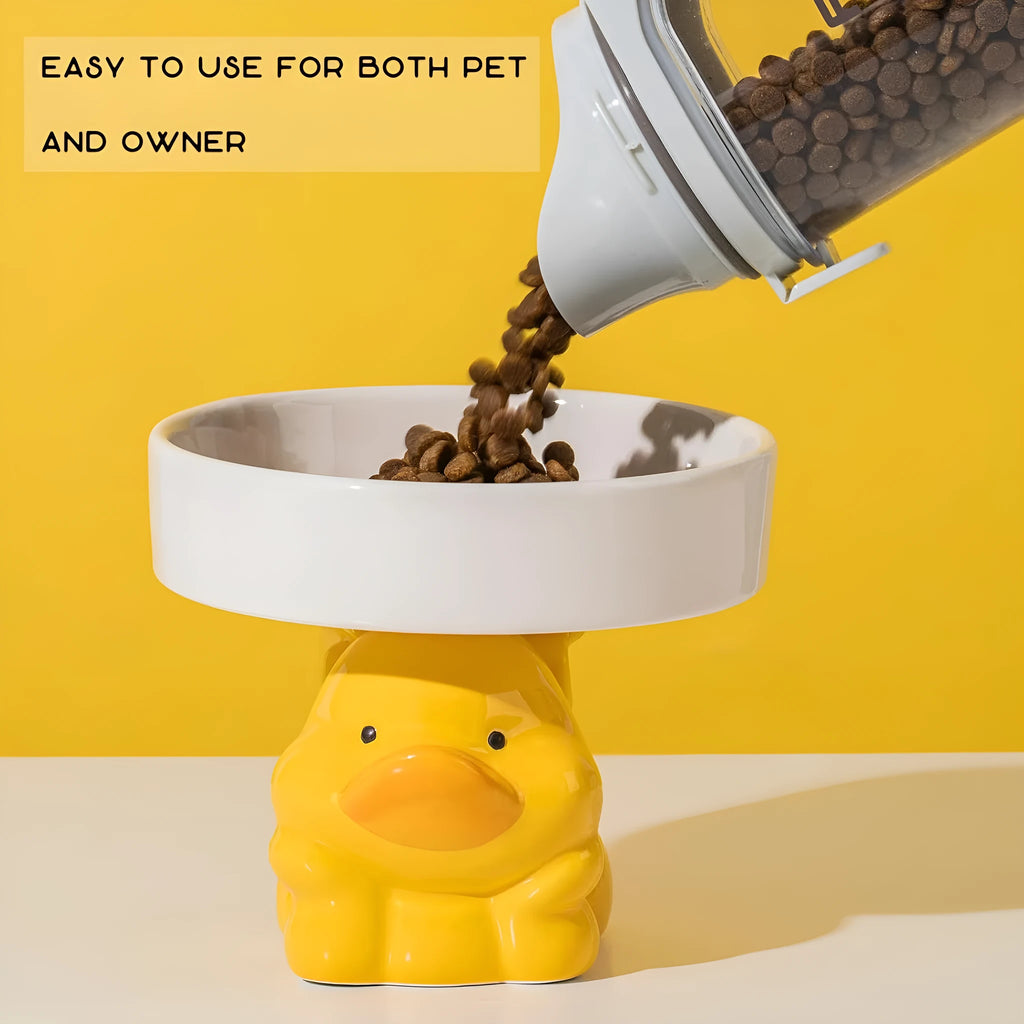 Raised ceramic cat bowl with animal design in pink, yellow, or white on a wooden floor.