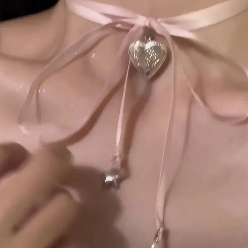 Close-up of a women's alloy necklace with a ribbed heart pendant on a clavicle-length chain.