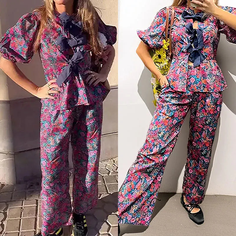 Women's floral print two-piece suit with a tie-neck puff sleeve top and matching trousers.