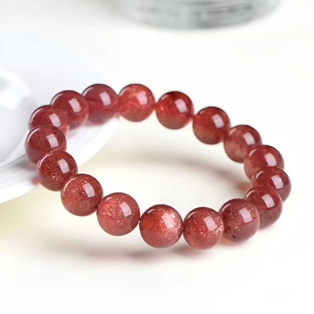 Natural strawberry quartz bracelet with geometry-shaped beads in starlight cherry red colour on a wrist.