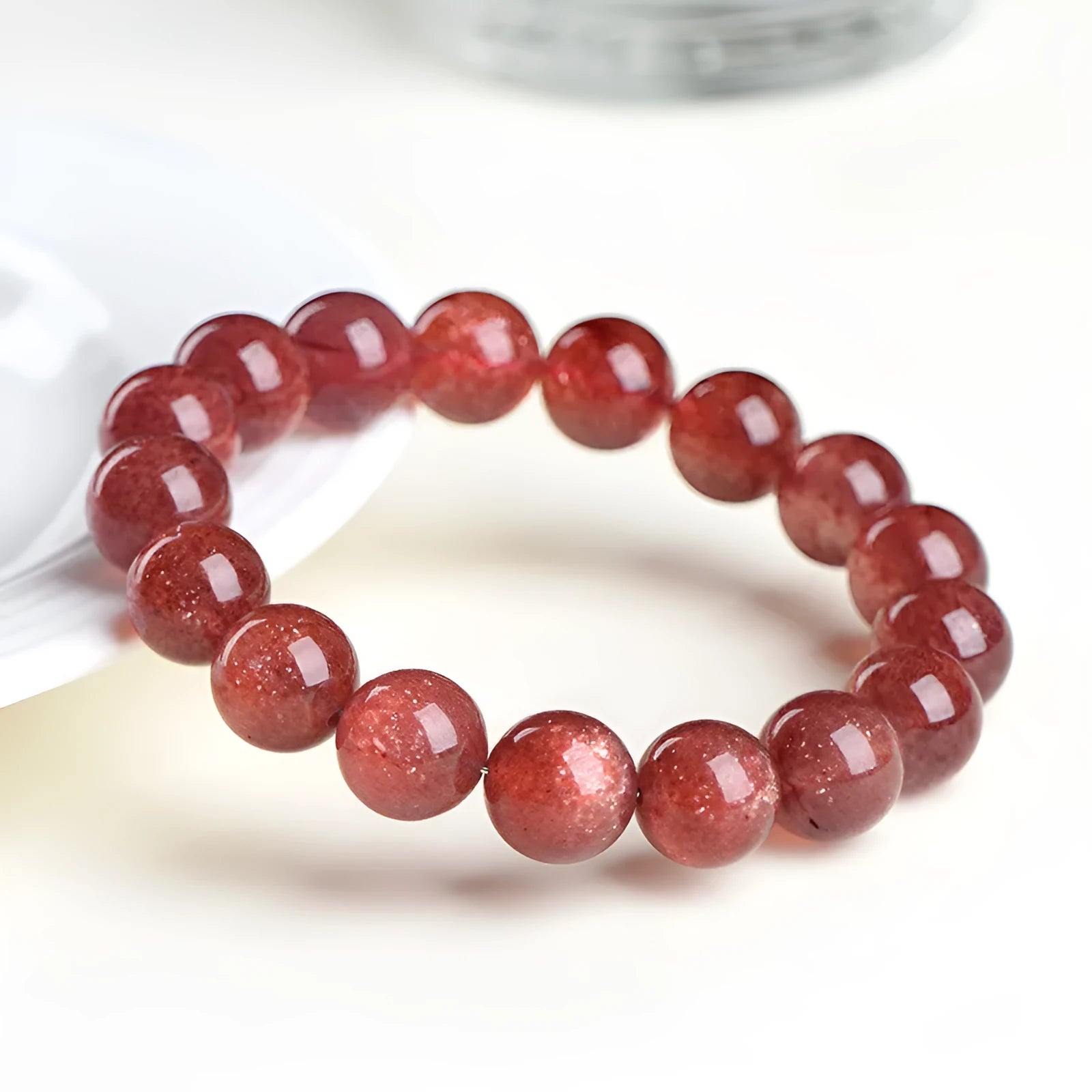 Natural strawberry quartz bracelet with geometry-shaped beads in starlight cherry red colour on a wrist.