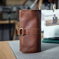 Handmade cow leather vintage wallet in black, showing tape extraction closure, 20cm long.