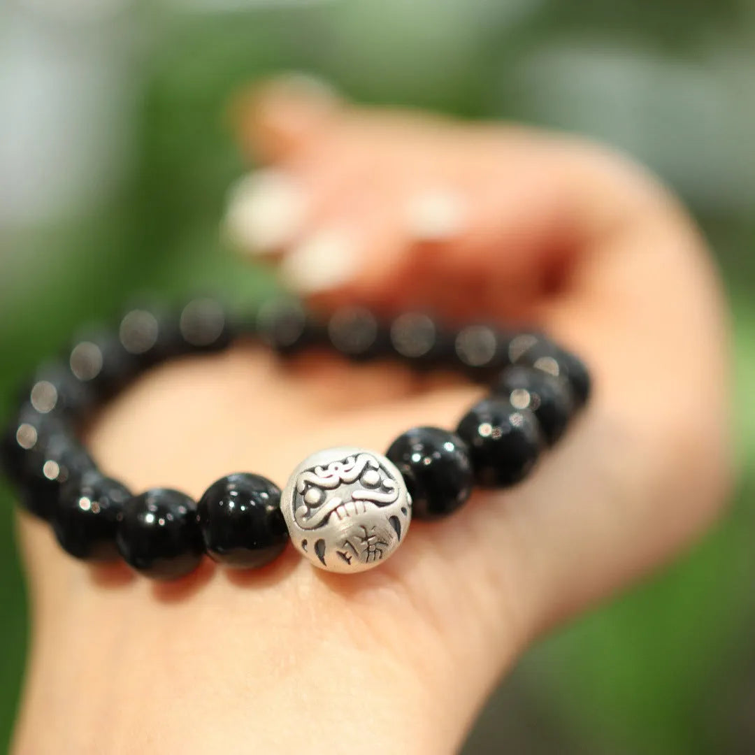Close-up of a women's black agate bead bracelet with a sterling silver clasp on a wrist.