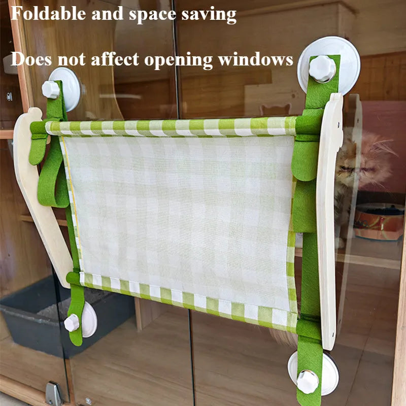 Wooden frame cat hammock with linen cushion mounted on a window, shown in green colour.