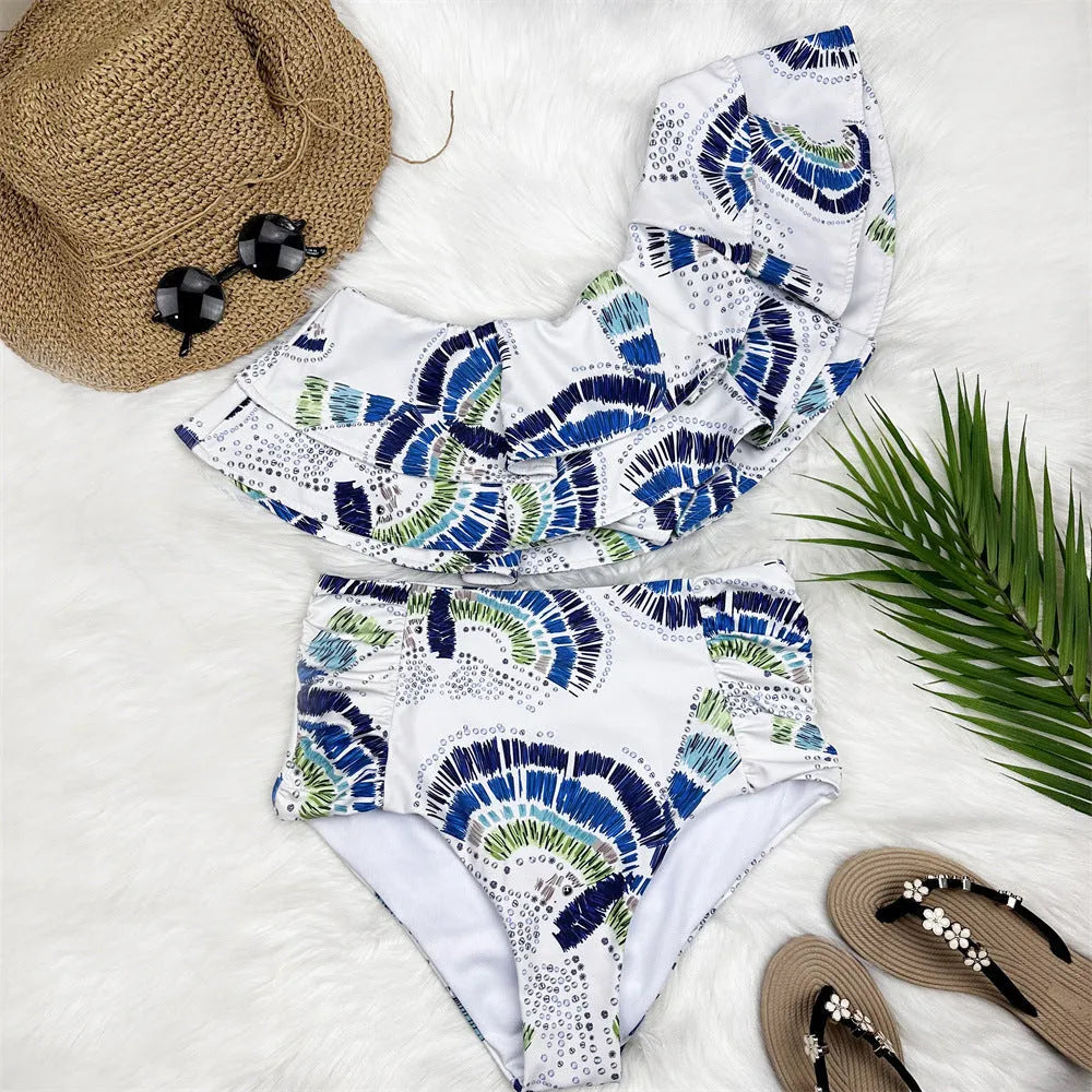 White women's one-shoulder swimsuit with a cascading lotus leaf ruffle and high-leg split.