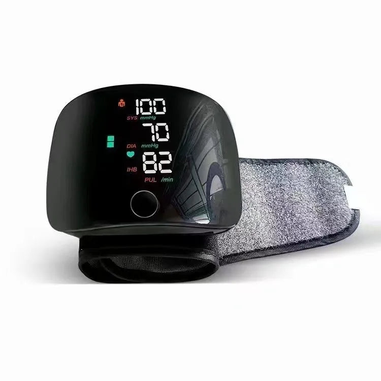 Black wrist blood pressure monitor with digital display, shown with USB charging cable.