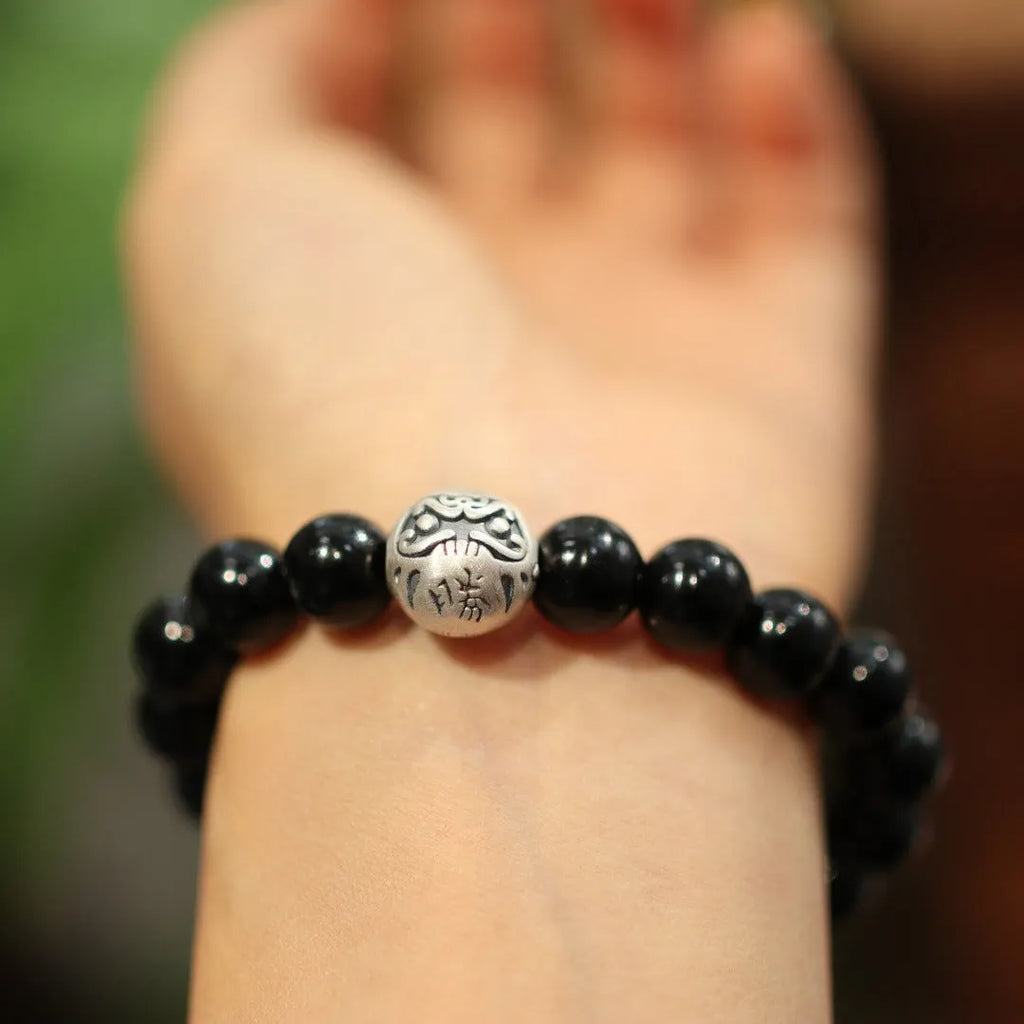 Close-up of a women's black agate bead bracelet with a sterling silver clasp on a wrist.