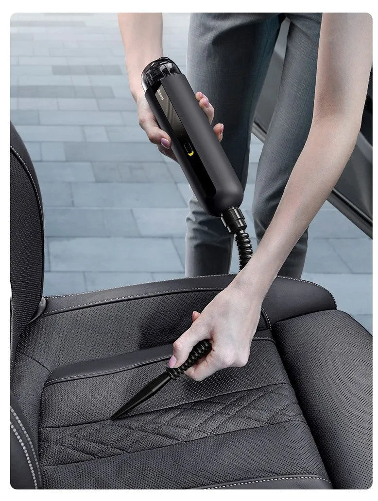 BASEUS black handheld car vacuum cleaner with hose on a car seat.