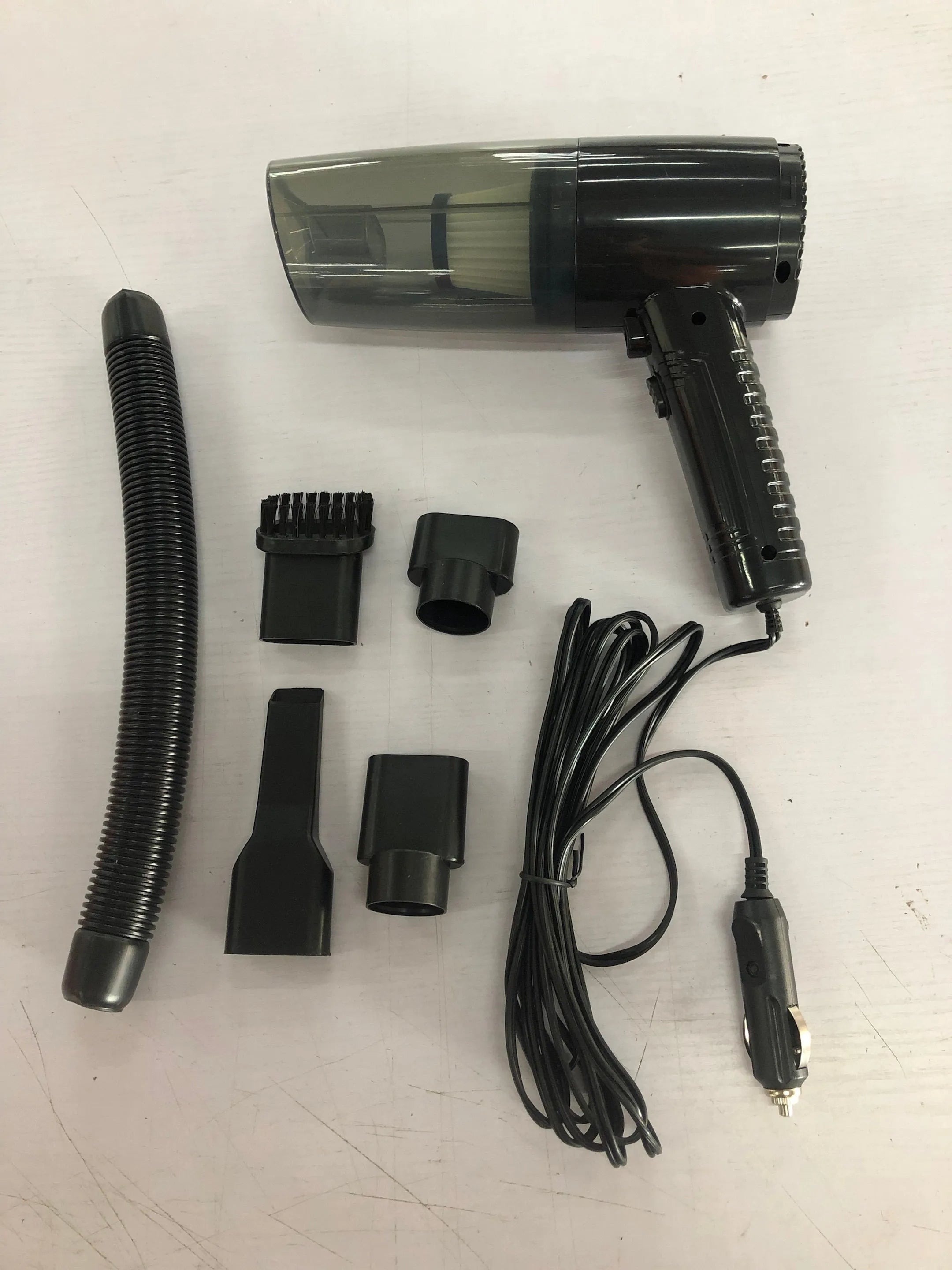 Black and white 12V car vacuum cleaner with long cable and five suction head accessories.