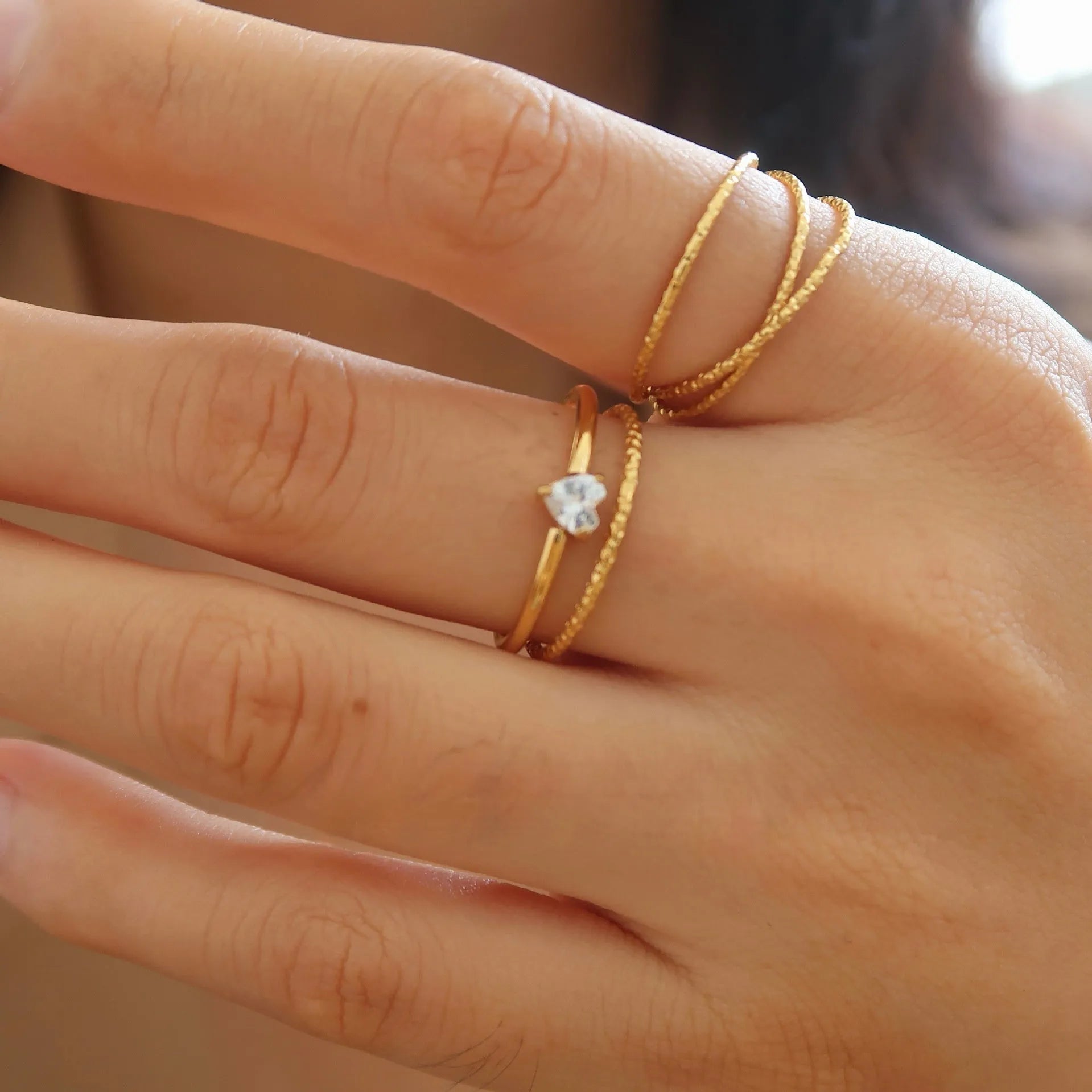 Golden electroplated stainless steel love heart ring and oval ring for women on a plain background.
