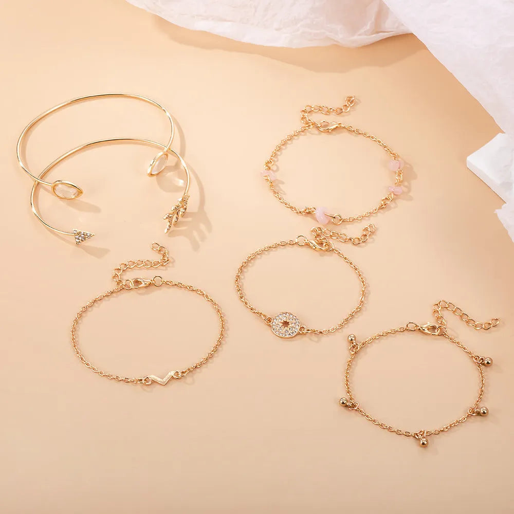 Gold-coloured six-piece women's bracelet set with arrow, water drop, and V-shaped charms on a white background.