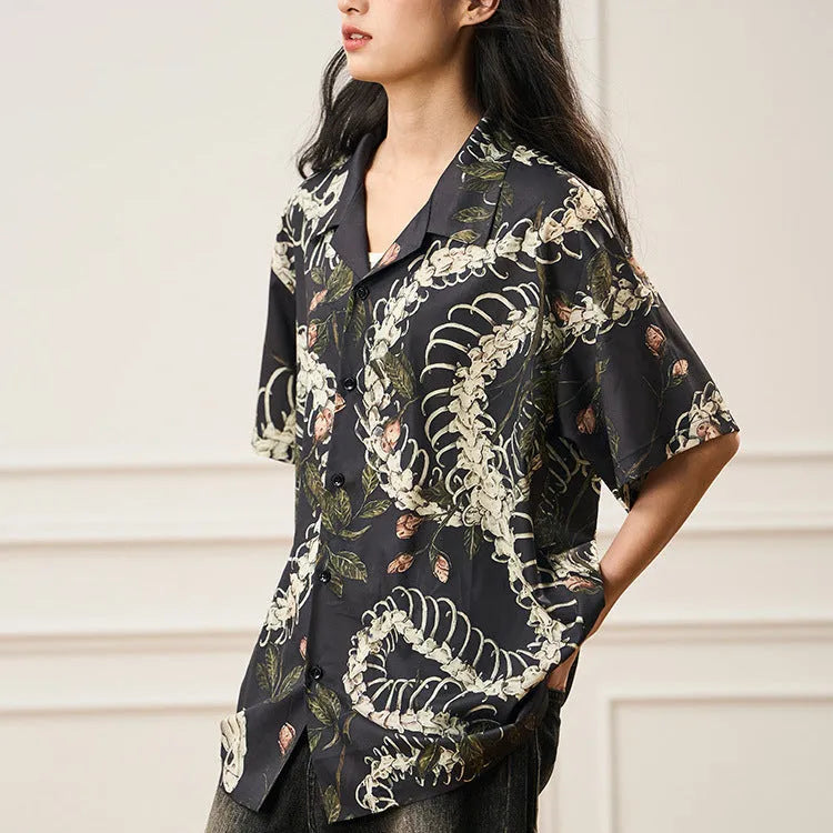 Man wearing a loose fit short sleeve Cuban collar shirt with a snake bone and floral pattern print.