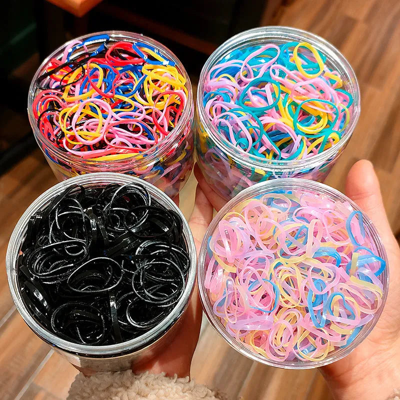 Pack of multicoloured thin TPU baby hair ties stored in a clear reusable plastic container.