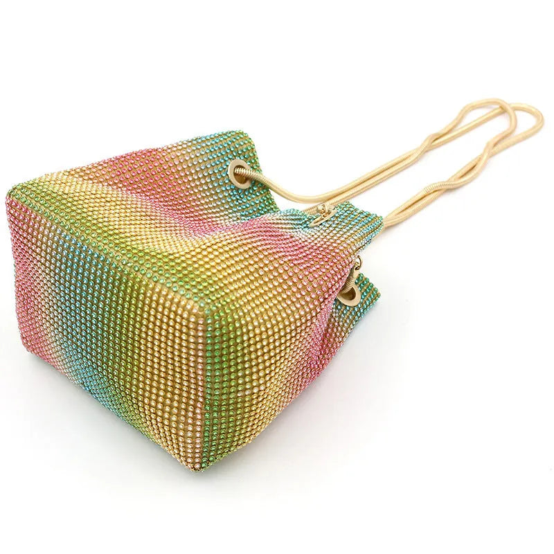 Soft rainbow-coloured rhinestone bucket bag with a silver chain shoulder strap on a white background.