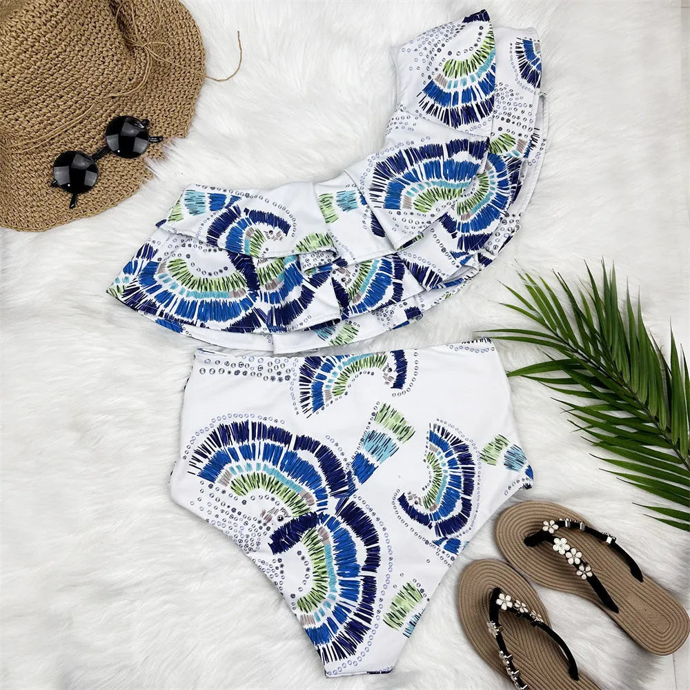 White women's one-shoulder swimsuit with a cascading lotus leaf ruffle and high-leg split.