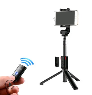 Black Bluetooth selfie stick tripod with remote control extended next to mobile phone