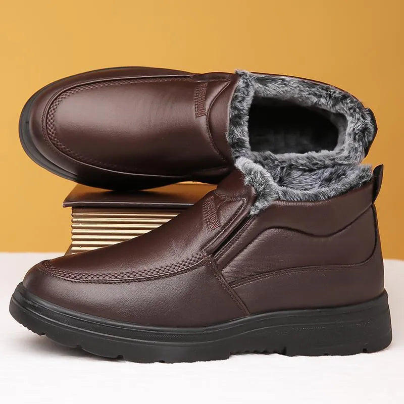 Men's black fleece-lined winter slip-on shoes with rubber sole on a wooden floor.