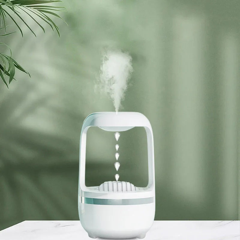 White anti-gravity water droplet humidifier on a wooden desk with visible mist and upward-flowing water beads.