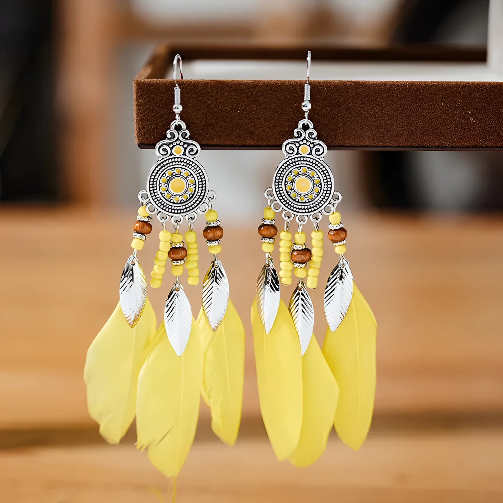 A pair of round drop leaf-shaped feather earrings in a chosen colour, showing Bohemian pattern details.