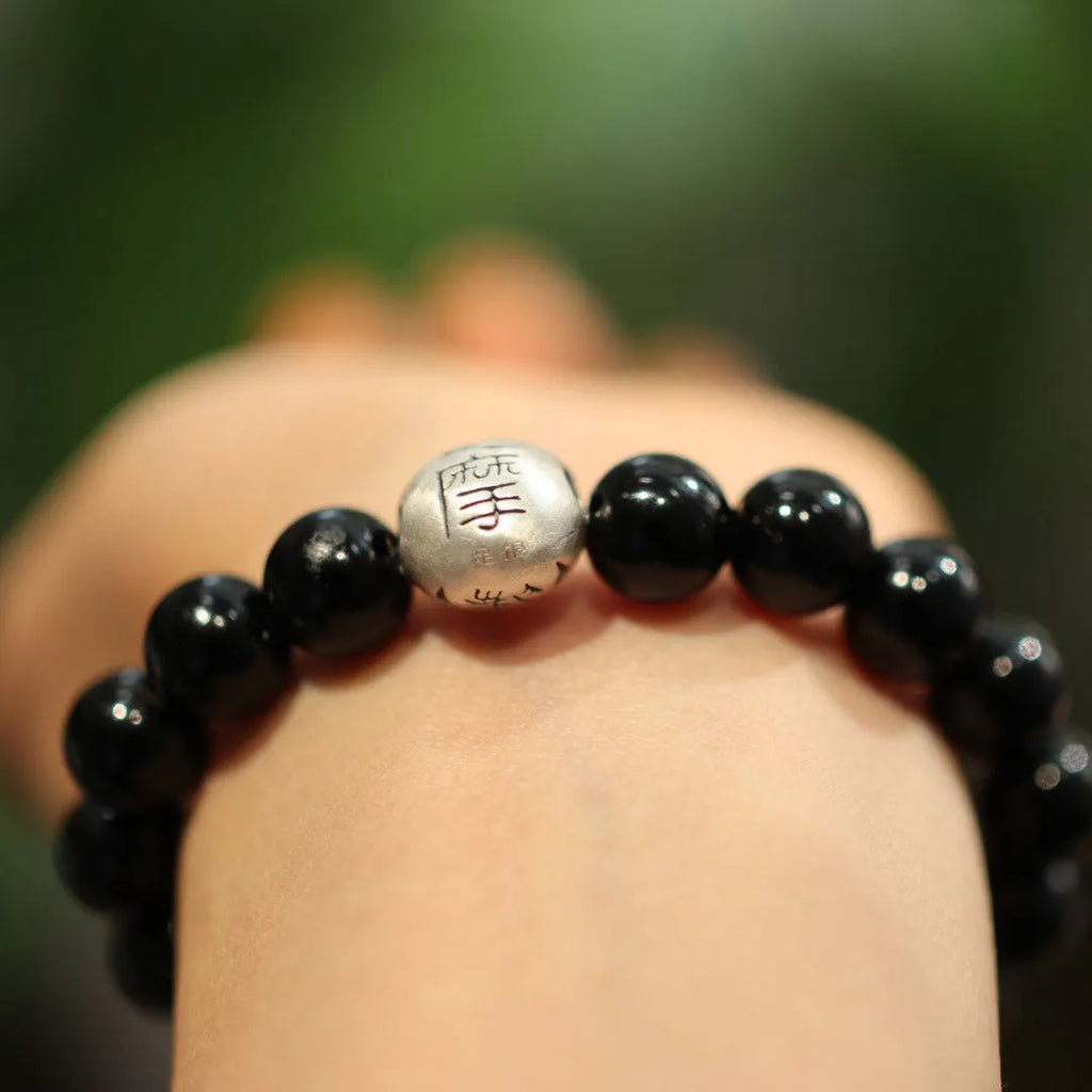 Close-up of a women's black agate bead bracelet with a sterling silver clasp on a wrist.