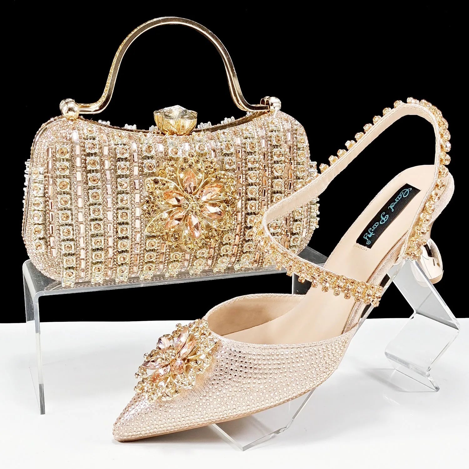 Women's black high heel sandals with ankle chain, floral rhinestone detail, and matching hard clutch bag