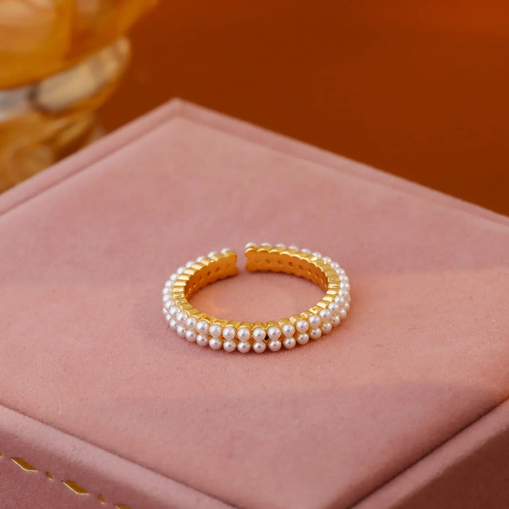 Gold-coloured women's open ring with geometric design and a round pearl-like bead.