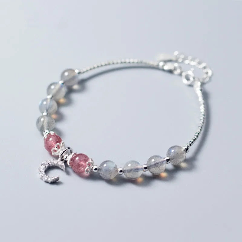 Handmade adjustable moonstone bracelet with crescent moon charm and crystal bead on wrist.