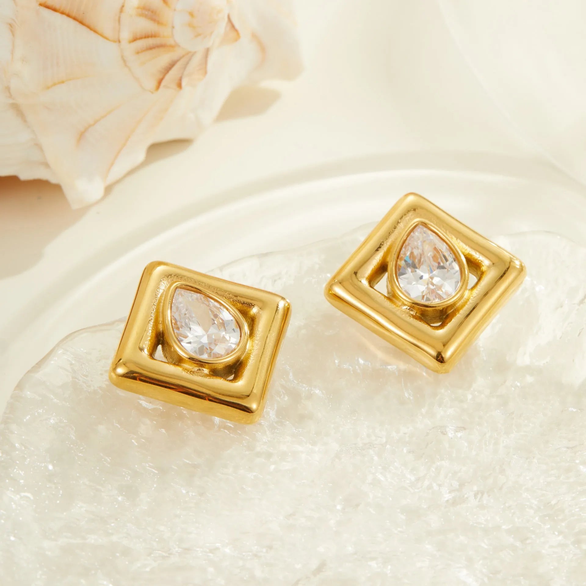 Pair of gold-coloured stainless steel stud earrings with geometric water drop zircon stone inlays.