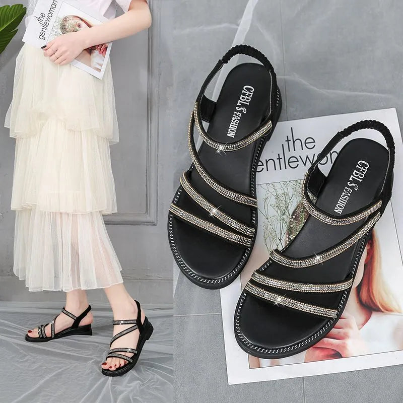 Women's silver flat sandals with rhinestone decoration and an elastic band across the foot.